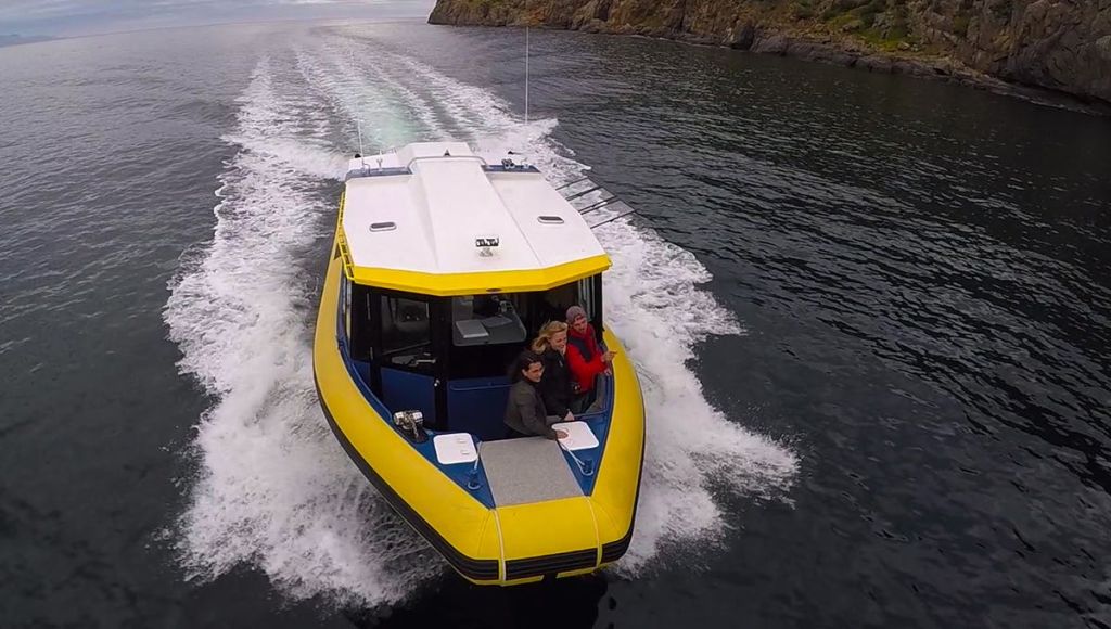 노란색과 흰색 보트에 세 명이 타고 물길을 따라 속도를 내며 절벽을 배경으로 잠에서 깨어납니다.