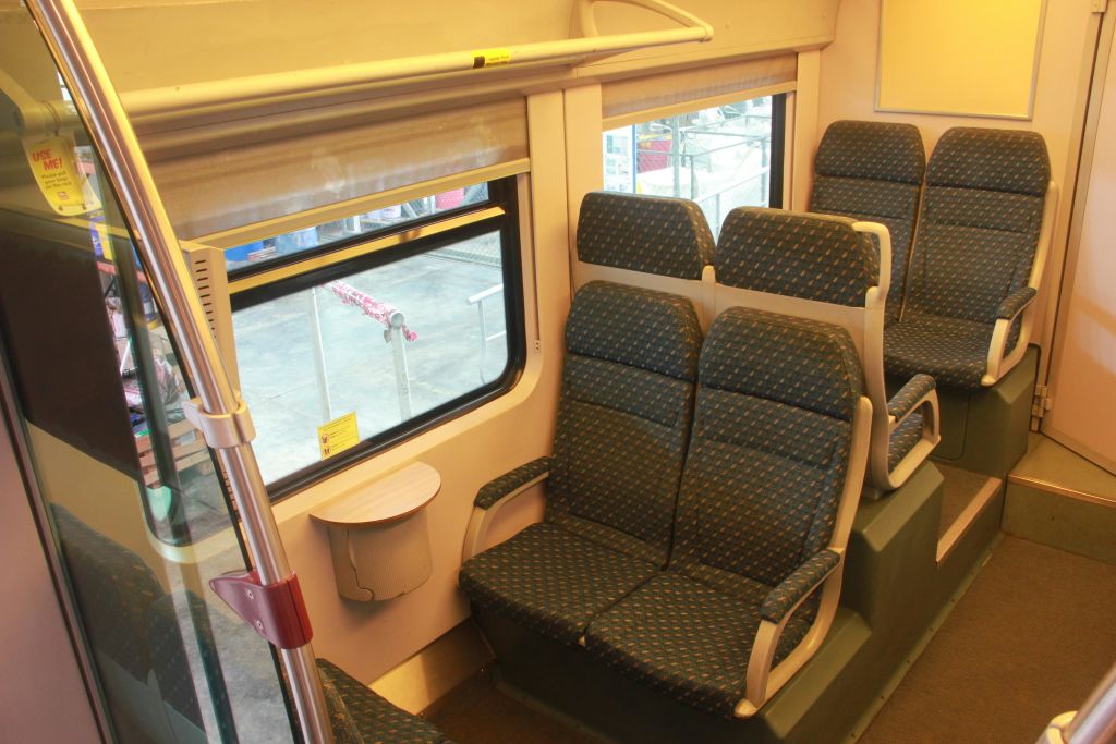 창문 옆에 무늬가 있는 빈 좌석이 있는 열차 내부. 창문 아래 벽에 작은 테이블이 붙어 있습니다.