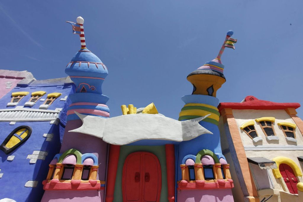 돔형 타워, 줄무늬 깃발, 맑고 푸른 하늘 아래 빨간색 이중 문 위의 빈 배너가 있는 화려하고 기발한 건물입니다.