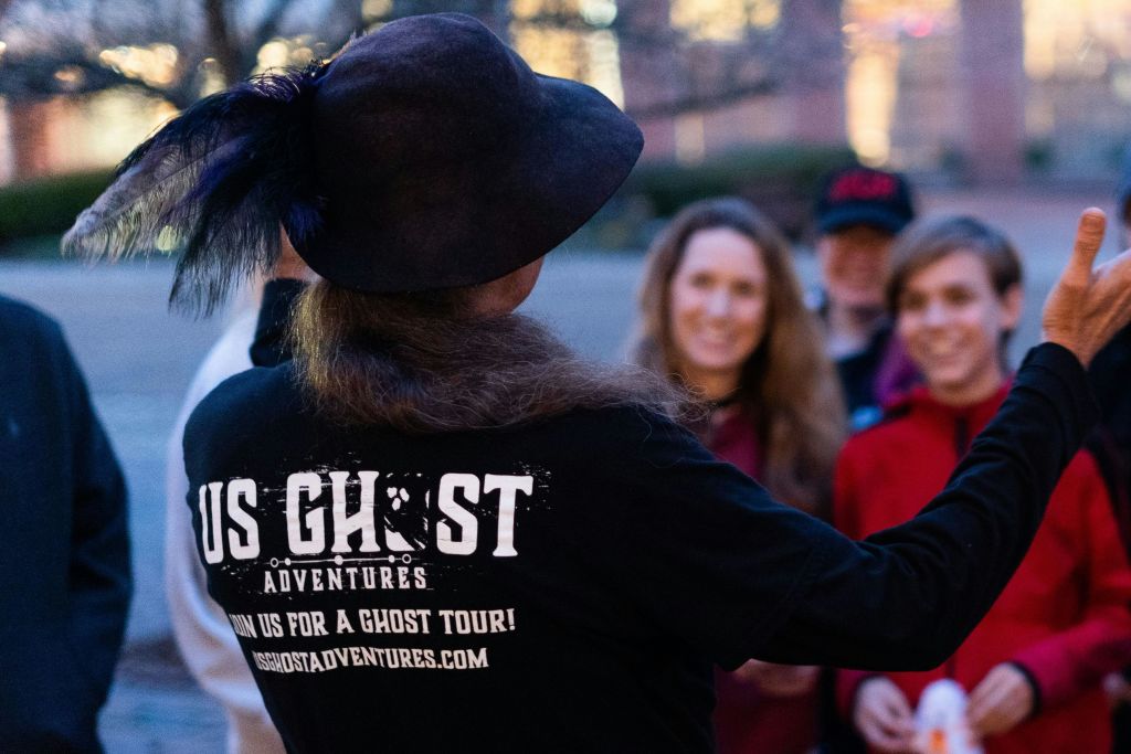 투어 가이드가 EMF 탐지기를 들고 있는 동안 그룹을 웃게 만들고 영적인 활동을 하는 동안