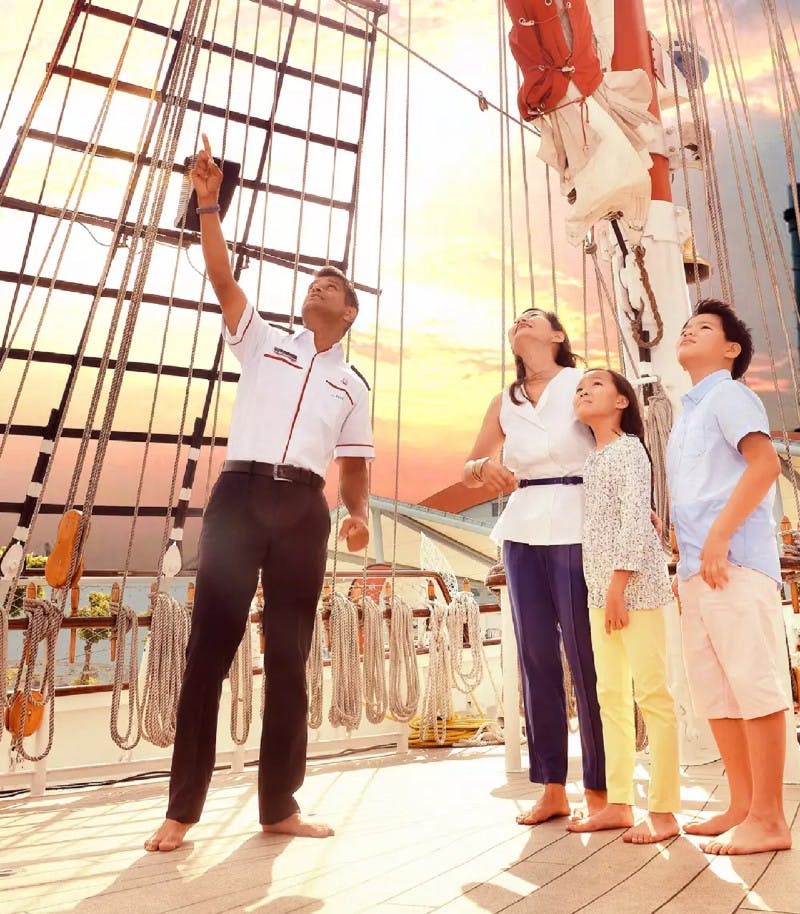 가족과 가이드가 선박 갑판에서 석양의 하늘을 배경으로 리깅을 바라보고 있습니다.