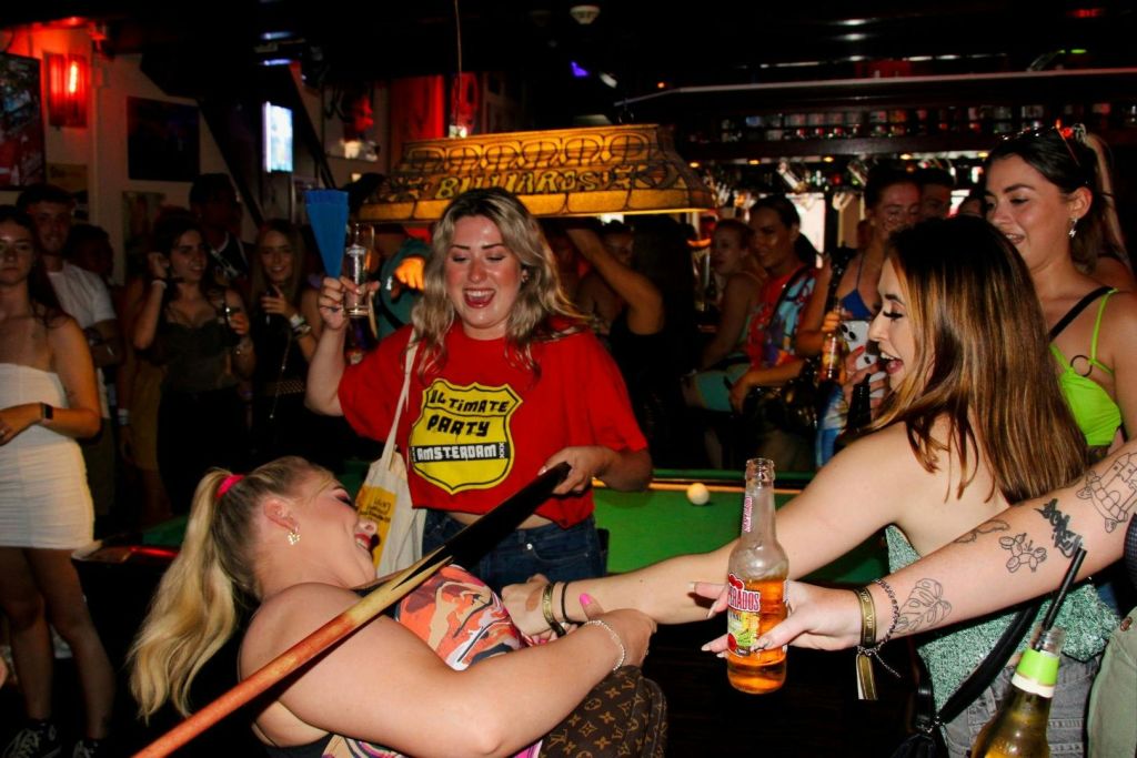 직원 중 한 명과 림보 게임을 하는 펍 크롤링 그룹의 사진.