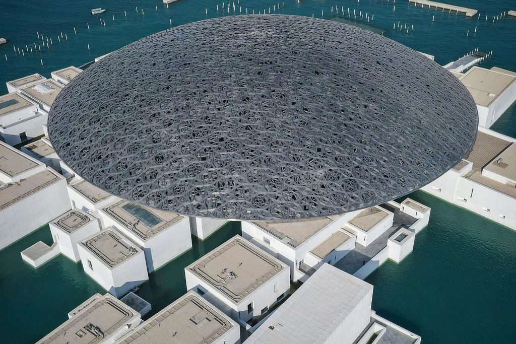 물로 둘러싸인 흰색 건물 위의 크고 복잡한 돔 구조의 공중 전망.
