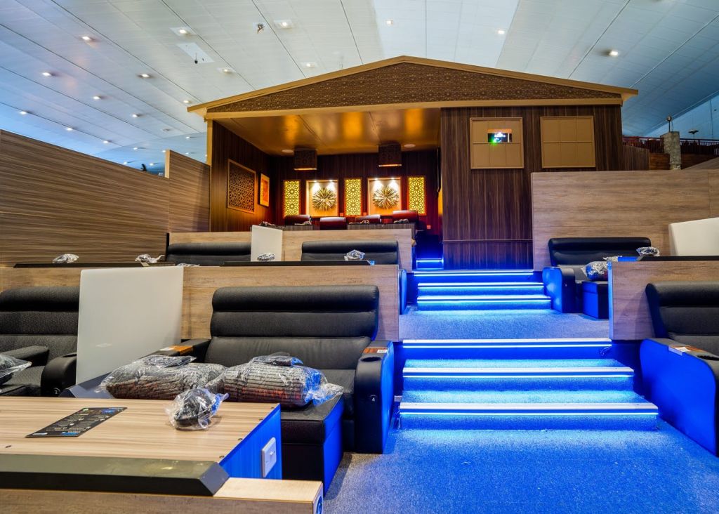 안락 의자, 파란색 계단이 있는 세련된 라운지, 벽에 장식 예술이 있는 목조 캐빈 스타일의 돌출된 공간.