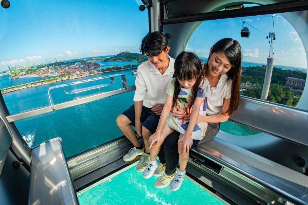 한 가족이 유리 바닥이 있는 케이블카에 앉아 물과 주변 풍경을 감상하고 있습니다.