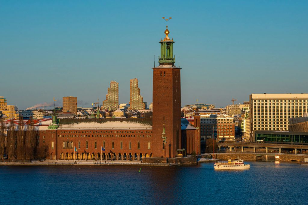 인근에 보트가 있고 현대적인 건물을 배경으로 물가에서 스톡홀름 시청의 전망을 감상할 수 있습니다.