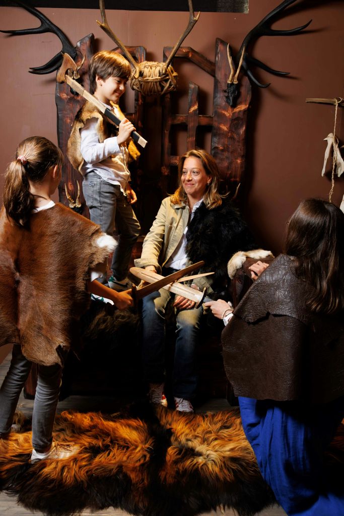 한 사람이 나무 왕좌에 앉아 사슴벌레에 둘러싸여 목검을 들고 있는 중세 의상을 입은 그룹.