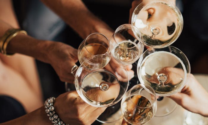 어두운 배경을 배경으로 위에서 바라본 화이트 와인이 가득한 다양한 종류의 와인 잔을 움켜쥐고 있는 몇몇의 손.