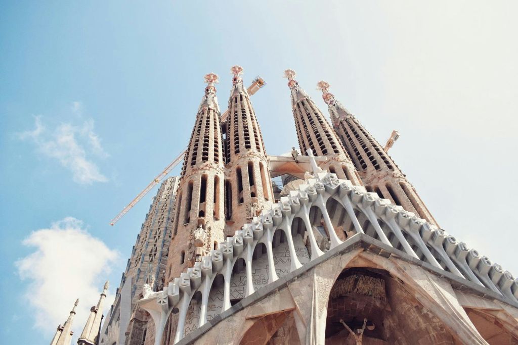 맑은 하늘을 배경으로 사그라다 파밀리아 (Sagrada Familia) 의 화려한 탑이 한눈에 들어옵니다. 배경에는 건설 크레인이 보입니다.