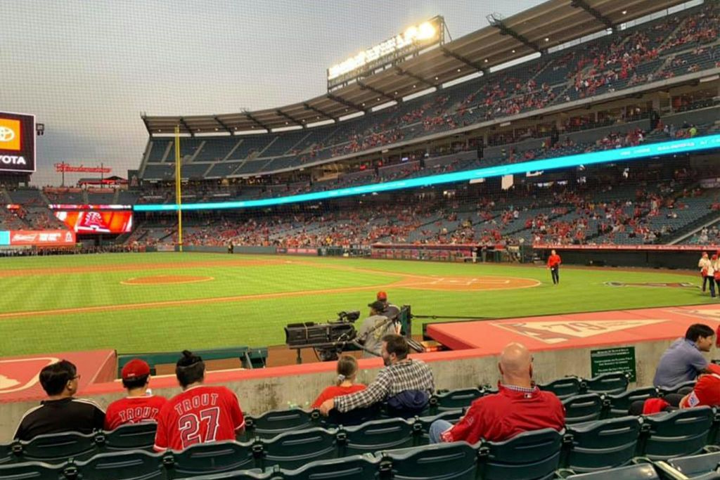 팬들이 스탠드에 앉아 필드의 전망을 감상할 수 있는 야구 경기장이 있으며, 멀리서 선수들이 워밍업하고 있습니다.