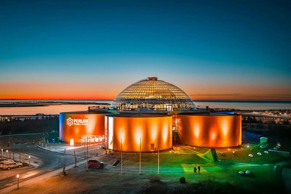 석양이 지면 주황색으로 빛나는 현대적인 돔 모양의 건물로, 전면에 '펄란' 이라는 글자가 보입니다.