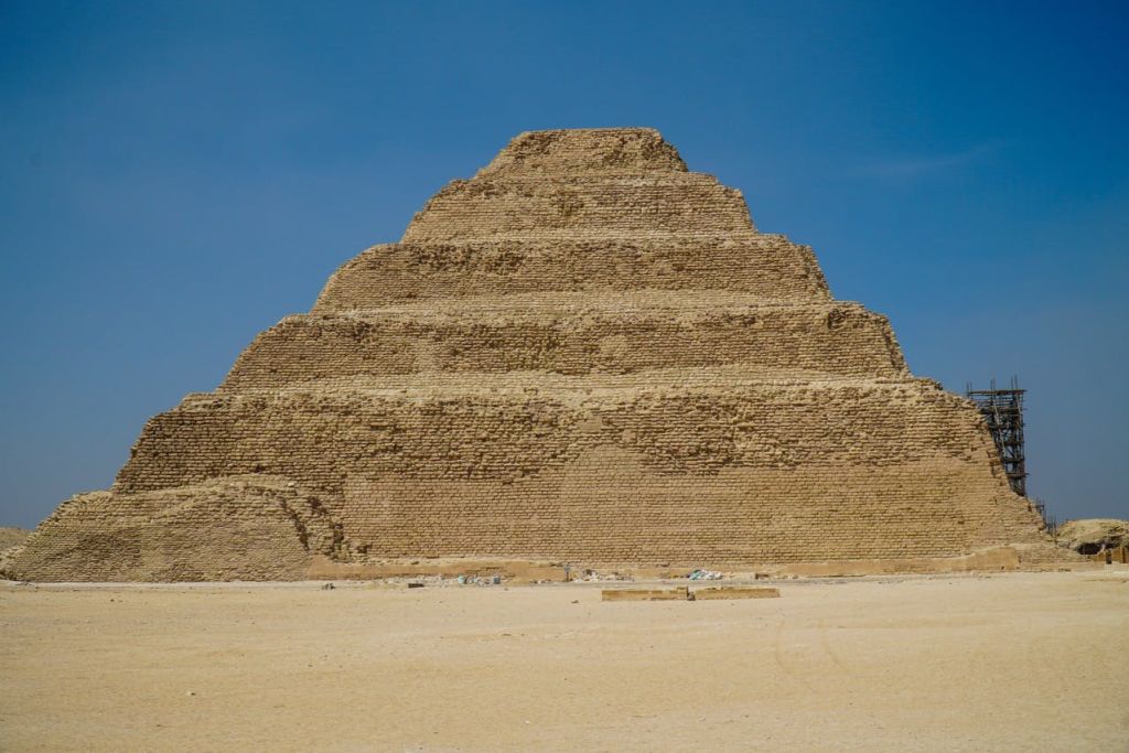 맑고 푸른 하늘 아래 사막 풍경의 계단식 피라미드 구조물.