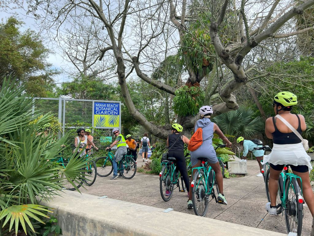 마이애미비치 식물원 입구에는 자전거를 탄 사람들이 나무와 식물을 배경으로 모여들었습니다.
