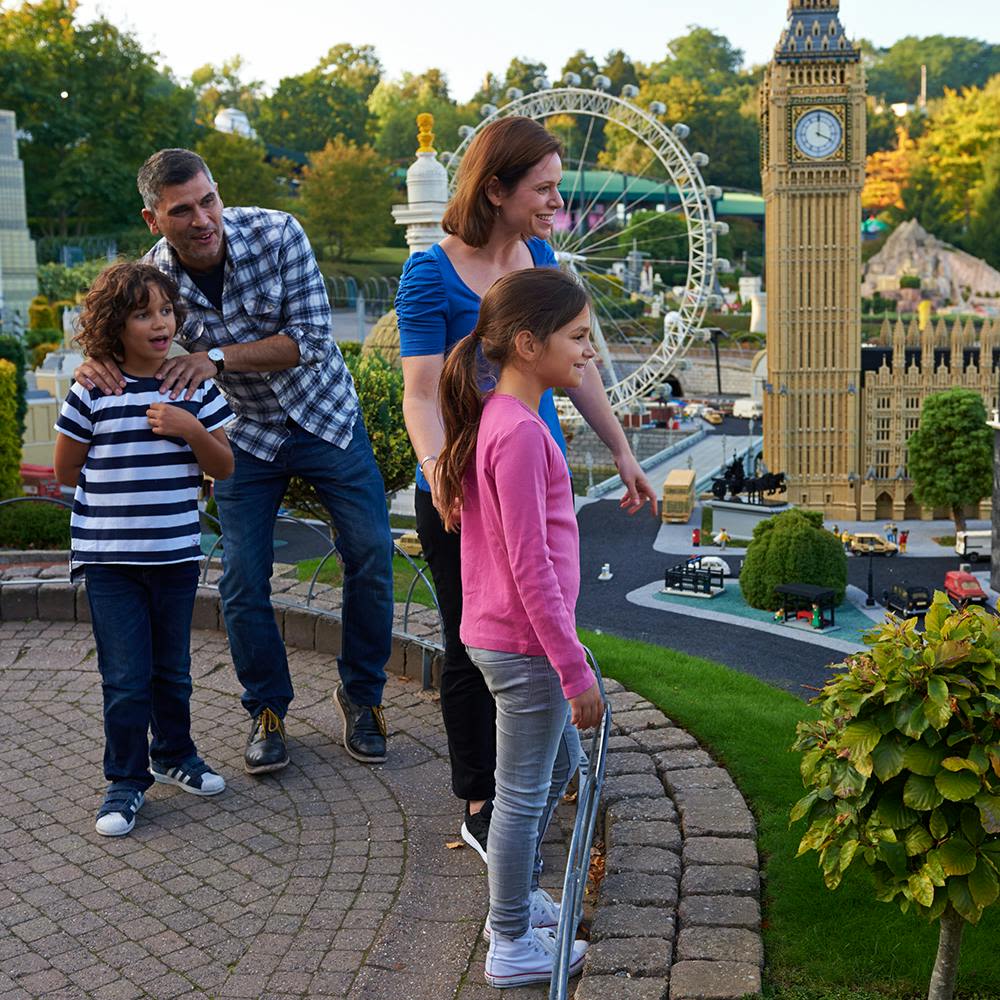 4인 가족이 야외 환경에서 빅벤과 런던 아이 등 런던의 미니어처 모델을 관찰합니다.