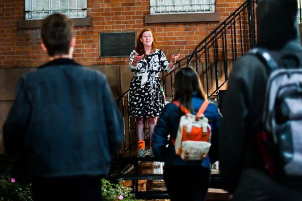 역사적인 건물 밖에서 그룹에게 이야기를 들려주는 표현력 있는 투어 가이드