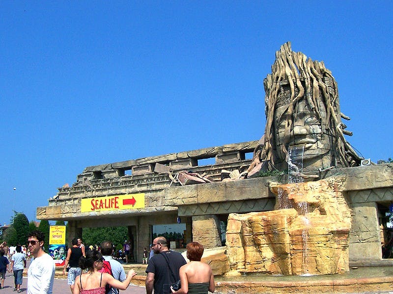 크고 바위가 많은 구조물과 맑고 푸른 하늘을 배경으로 '바다 생명체' 로 표시된 입구 근처를 걷는 사람들.