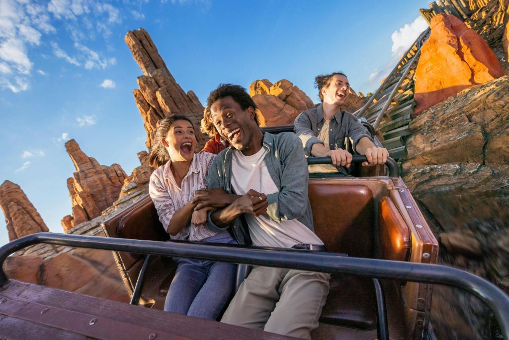 빅 썬더 마운틴 (Big Thunder Mountain) 어트랙션에 있는 두 명의 청년 커플이 몸을 구부리며 비명을 지르고 있습니다.