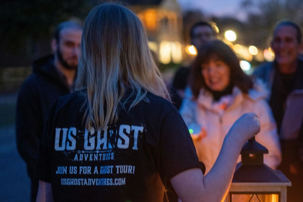 게스트가 귀신 이야기를 듣기 위해 주변을 둘러싸고 있을 때 등불을 들고 있는 투어 가이드