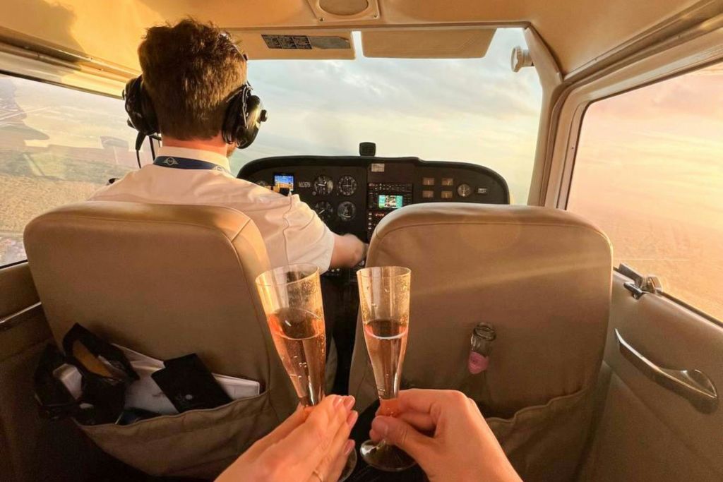샴페인 안경을 끼고 두 손으로 작은 항공기를 조종하는 조종사.
