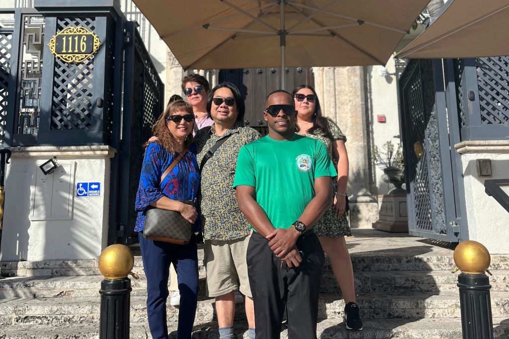 투어 가이드가 일행과 함께 베르사체 저택 앞에서 포즈를 취하고 있습니다.