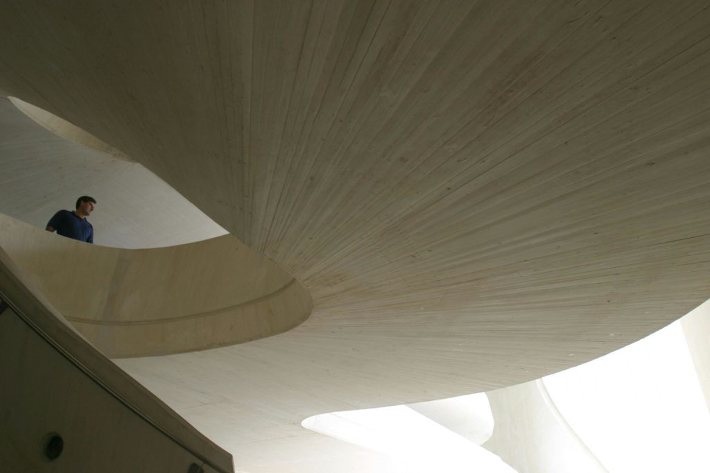 매끄러운 선과 교차하는 평면이 특징인 현대적인 건축 디자인의 곡선형 밝은 색 콘크리트 구조.