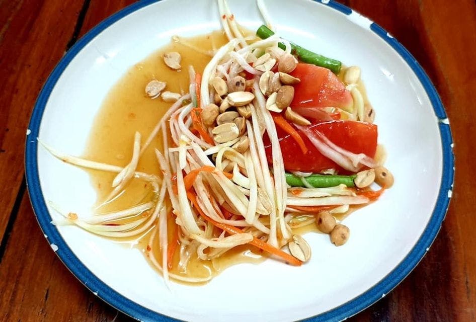 잘게 썬 파파야, 토마토, 녹두, 땅콩, 가벼운 드레싱을 곁들인 태국식 파파야 샐러드 한 접시.