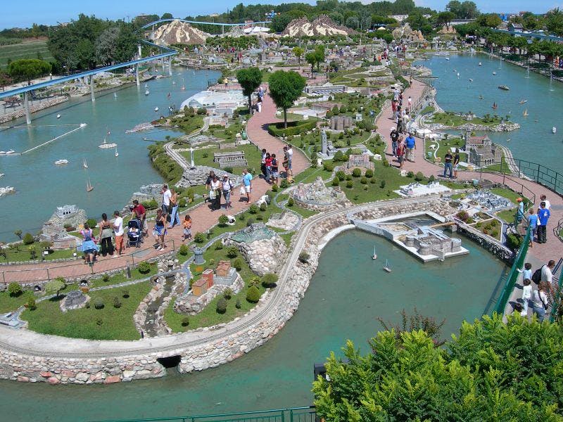 모형 건물, 통로, 물놀이 시설, 미니어처를 걷고 관찰하는 방문객이 있는 미니어처 공원의 공중 전망.