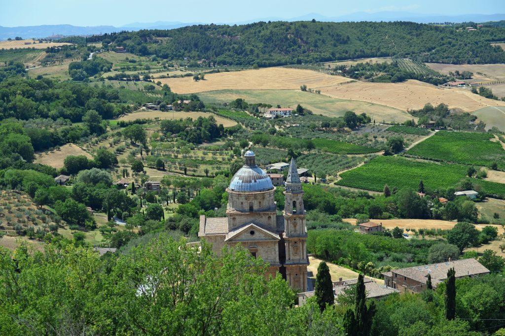 돔과 타워가 있는 유서 깊은 교회는 푸른 하늘 아래 울창한 언덕과 들판, 흩어져 있는 건물로 둘러싸여 있습니다.