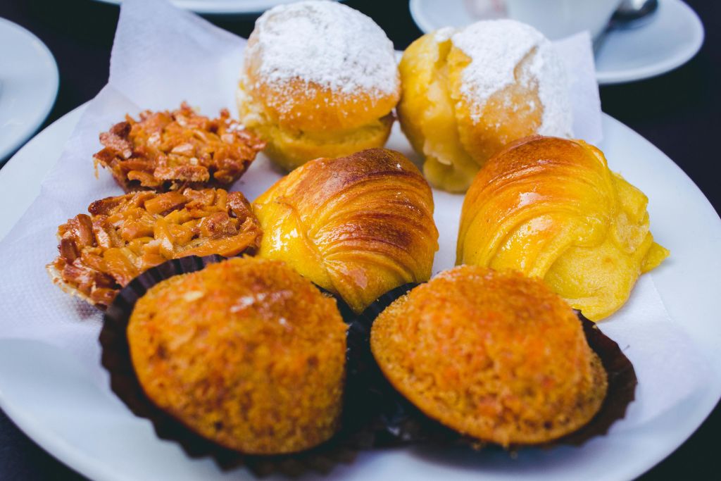 가루로 만든 설탕 얹은 빵, 크루아상, 각질이 얇고 부스러진 디저트를 포함한 다양한 패스트리를 접시에 담습니다.