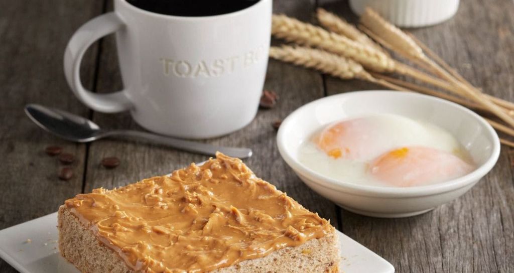 땅콩 버터가 담긴 빵 한 조각, 삶은 달걀 두 개가 담긴 그릇, 밀 줄기, "토스트" 가 양각된 흰색 머그잔.