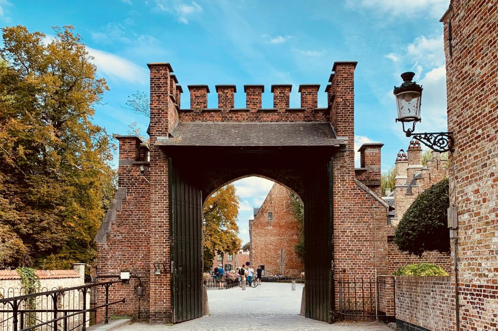 푸른 하늘 아래 배경을 걷고 있는 사람들이 있는 벽돌로 된 성문의 아치형 통로.