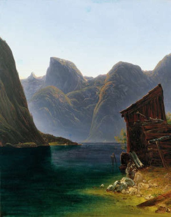 맑은 하늘 아래 바닷가에 풍화된 나무 오두막이 우뚝 솟은 산으로 둘러싸인 고요한 호수.