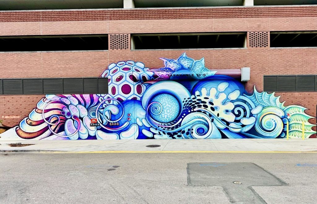 파란색, 보라색, 흰색의 그늘에서 소용돌이치는 무늬, 산호, 바다 생물을 테마로 한 생동감 넘치는 벽화입니다.