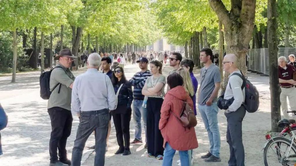 공원의 가로수 길에 서 있는 한 무리의 사람들로, 근처에 배낭과 자전거를 착용하고 있습니다.