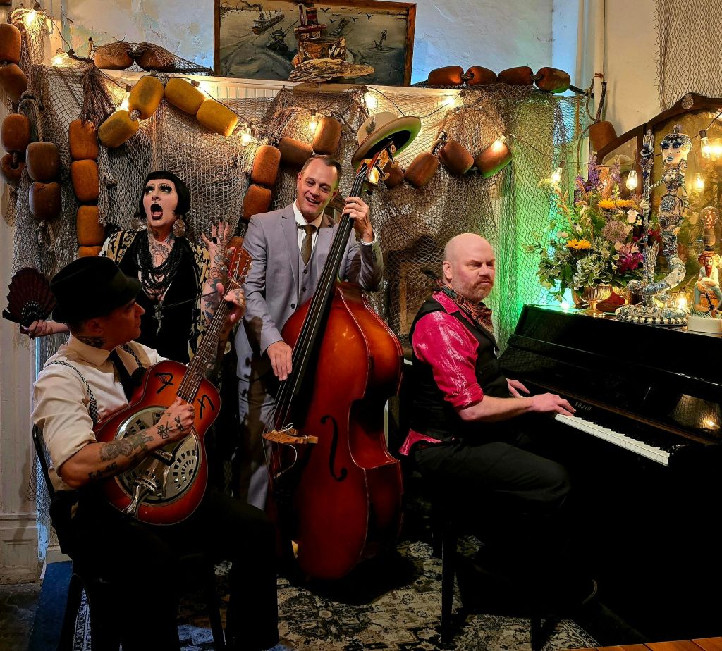 기타리스트, 베이시스트, 피아니스트, 보컬리스트가 참여하는 4명의 뮤지션이 아늑한 분위기에서 공연하며, 해상 인테리어가 돋보입니다.