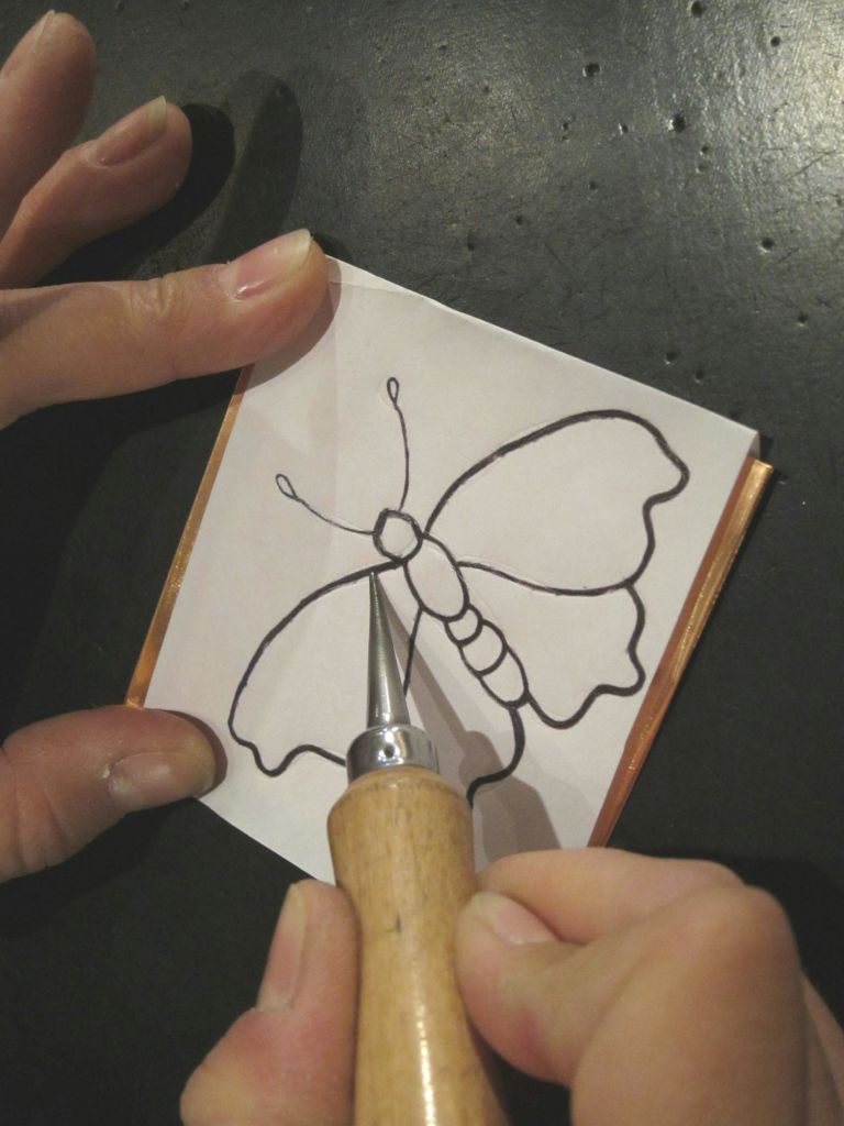 도구가 새겨진 나비 모양의 종이를 들고 있는 손.