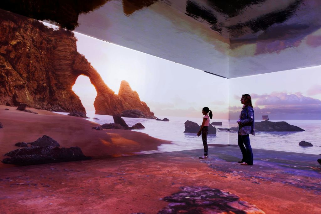 벽과 바닥이 있는 방에 있는 두 사람은 바위 지층과 석양이 있는 경치 좋은 해변을 전시하고 있습니다.