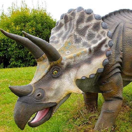 관목을 배경으로 잔디에 위치한 세 개의 뿔과 프릴을 보여주는 디테일한 질감의 트리케라톱스 모델.