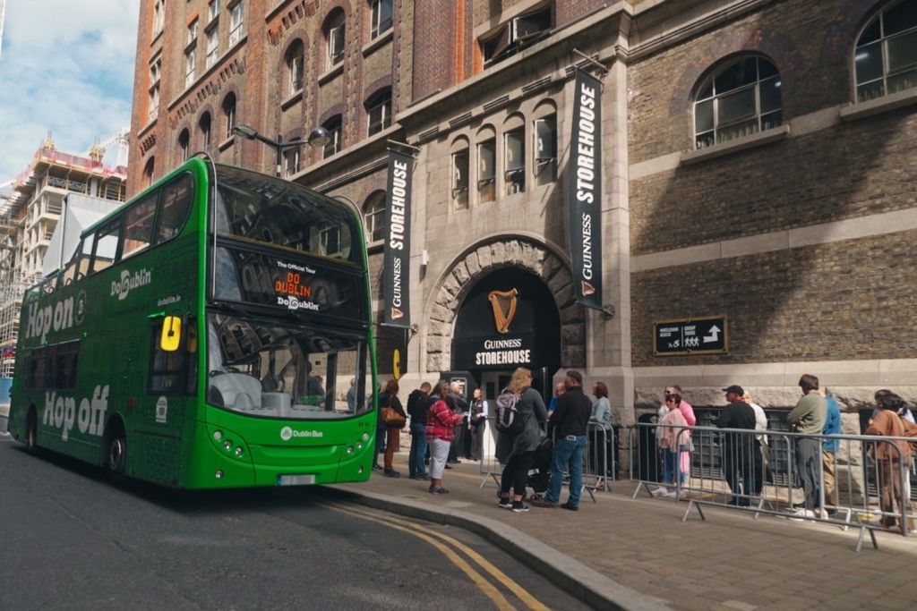 초록색 버스가 갈색 건물 앞에 주차되어 있습니다.