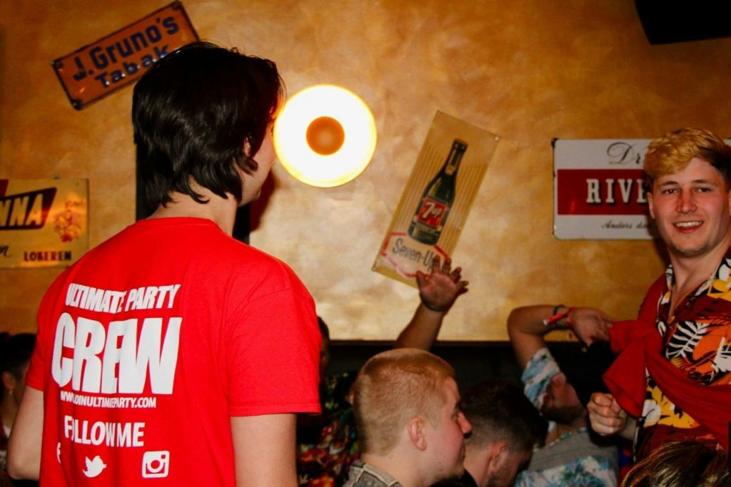 펍을 기어다니는 일행이 앉아 있고 직원이 서 있는 사진입니다.