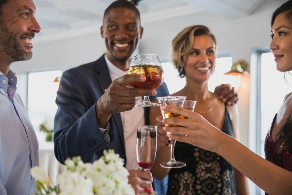 정장 차림의 세 사람이 축하용 토스트에 안경을 끼고 서로를 향해 미소를 짓고 있습니다.