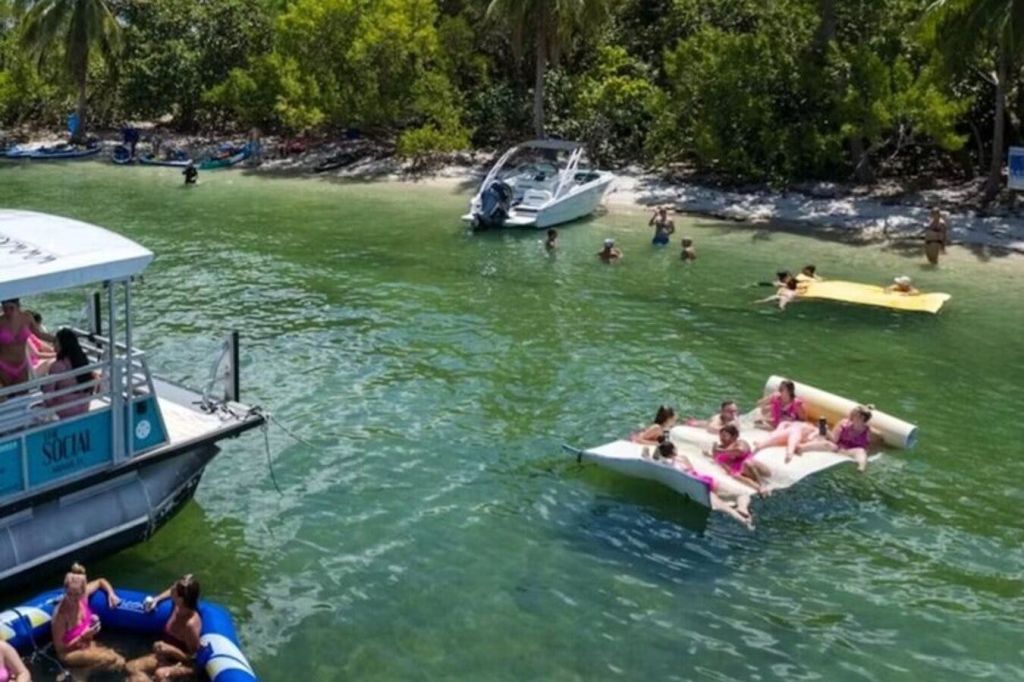 섬의 해안가에 정박한 보트, 대형 뗏목을 타고 해변의 레저를 즐기는 사람들 - 목가적인 바다 탈출의 순간.