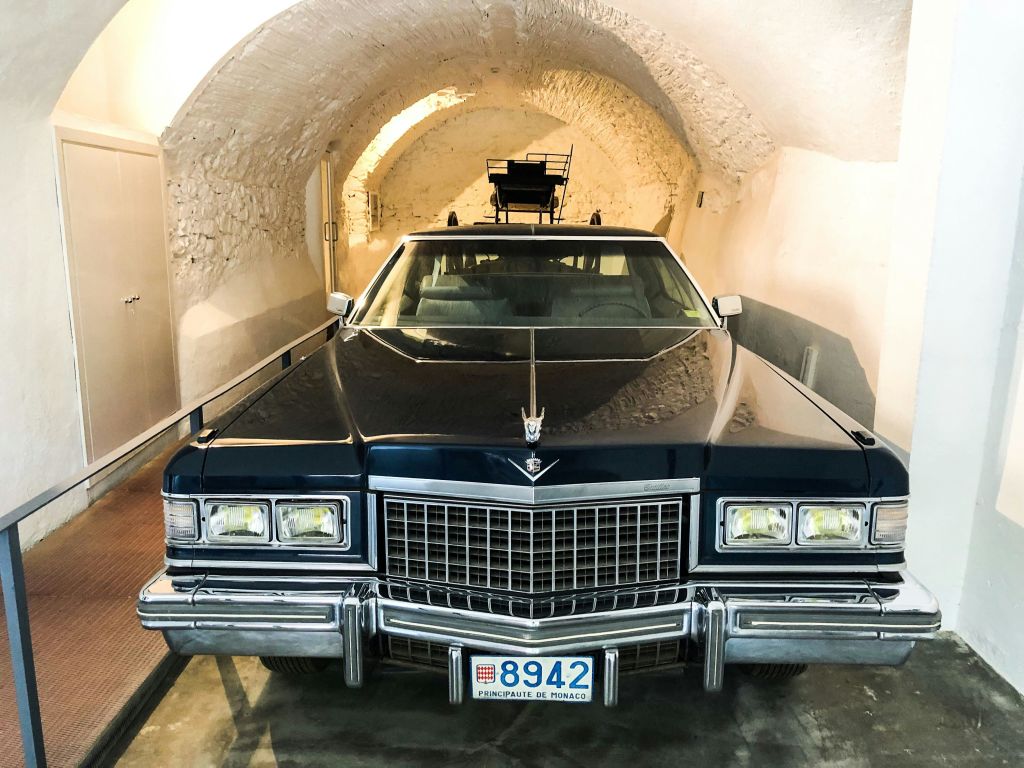 아치형 석조 차고에 주차된 모나코 번호판이 있는 고전적인 검은색 자동차입니다.