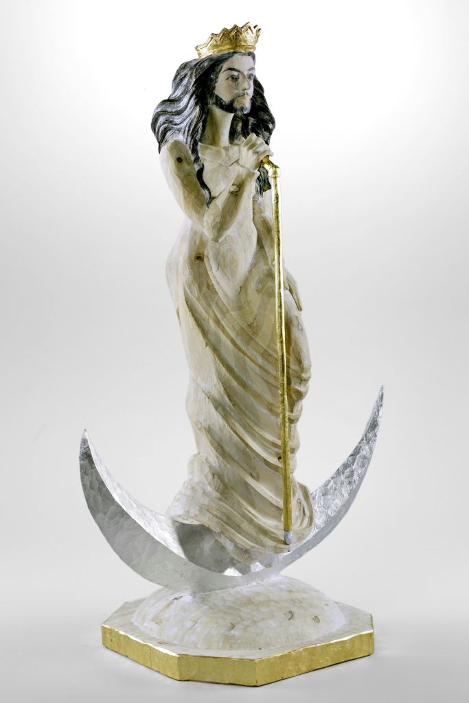 왕관과 긴 머리카락, 검이 달린 수염이 흐르는 가운을 두른 나무 조각상.