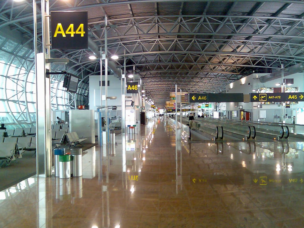 높은 천장, 게이트 표지판 (A44, A46), 움직이는 통로, 광택 있는 바닥이 있는 빈 공항 터미널.