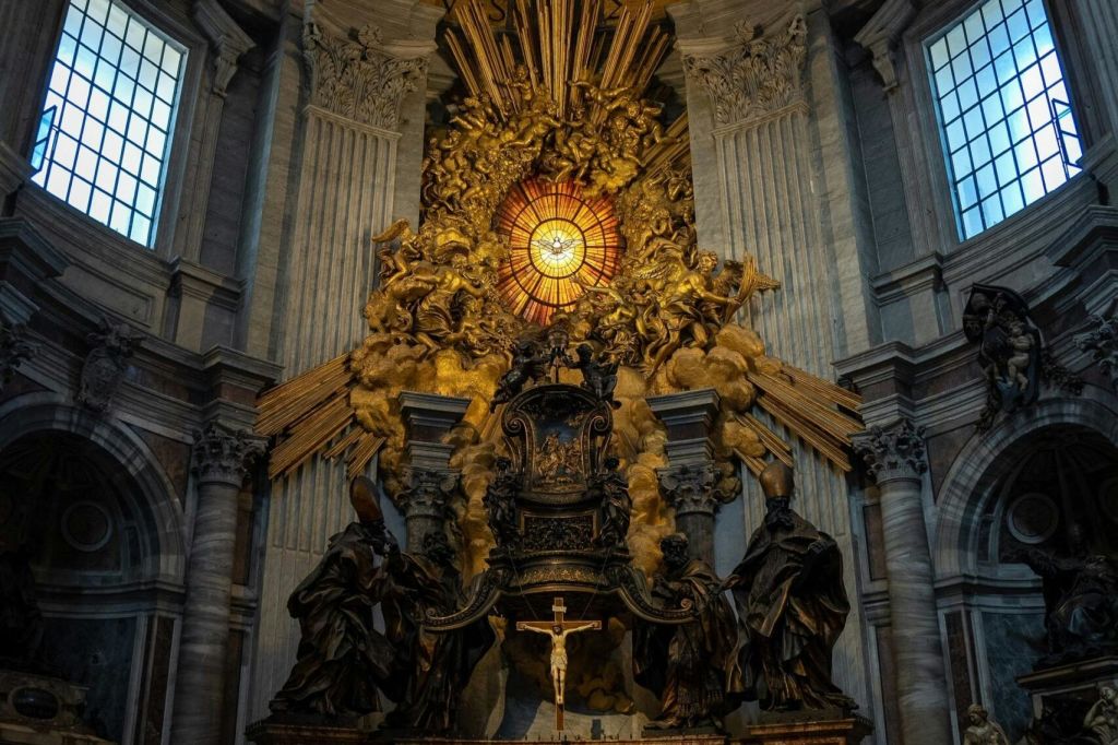 십자가와 스테인드글라스 창을 중심으로 금빛 햇살이 내리쬐는 종교 제단, 천사, 인물이 화려하게 장식되어 있습니다.