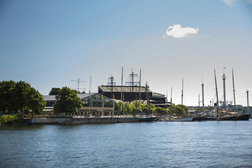 해안가를 따라 정박한 보트, 건물, 맑고 푸른 하늘을 배경으로 한 박물관이 수변에 펼쳐집니다.