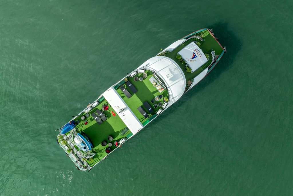 초록색 인조 잔디가 깔린 보트, 휴식 공간, 캐노피 커버가 있는 바다 위를 항해하는 모습.