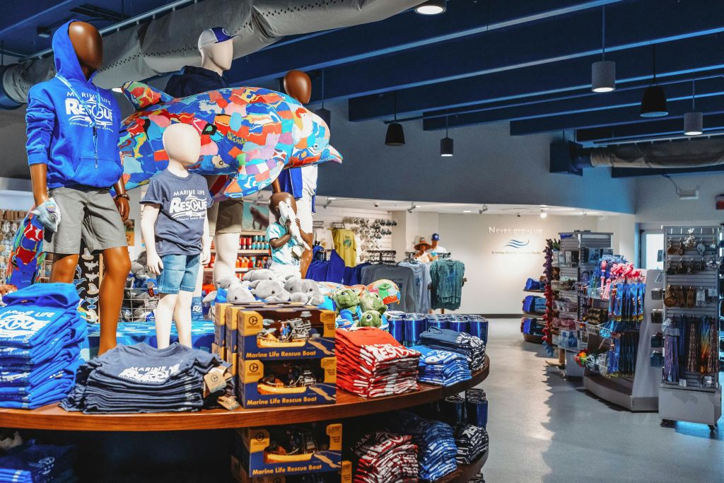 마네킹, 아동복, 고급 장난감 및 기타 기념품이 있는 기프트숍 인테리어. 트랙 조명이 있는 파란색 천장.