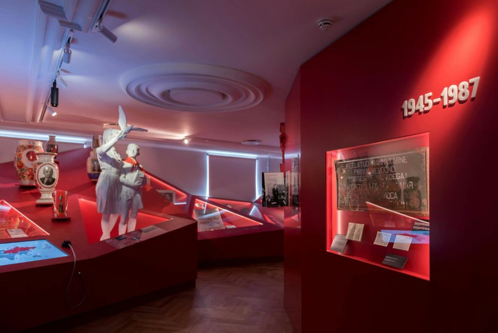 붉은 벽, 기간 의류의 마네킹, 조명 디스플레이 케이스가 있는 박물관 전시실.